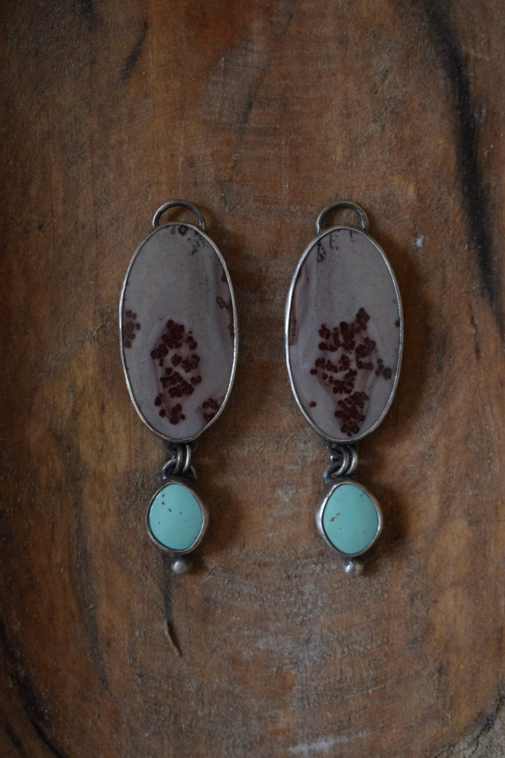 These earrings have two large maroon and grey stones with a marbled print, below them hangs light green turquoise dangles with small silver dot accents.